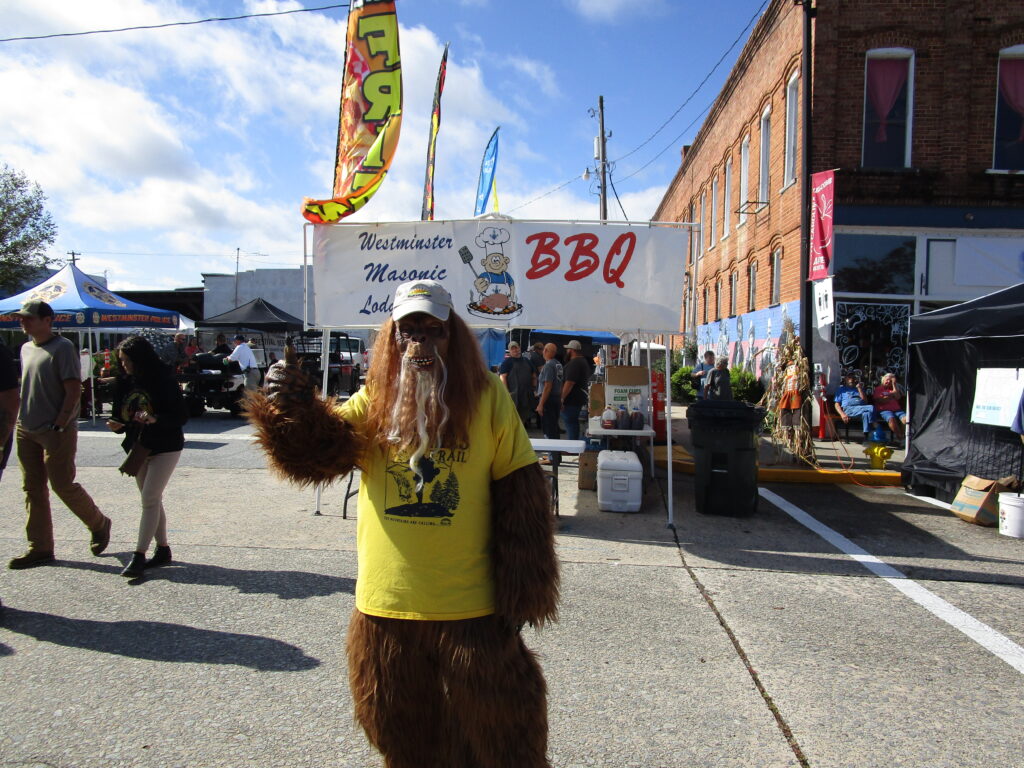 A person in a Bigfoot costume standing on main street.